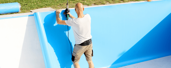 Hombre instando liner azul en piscina